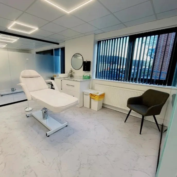 Fully equipped aesthetic treatment room with couch, basin and seating